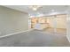 Open-concept living area with neutral-toned carpet, a partial kitchen view, and bright recessed lighting at 5836 Spruce Creek Woods Dr, Port Orange, FL 32127