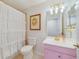 Well-lit bathroom featuring pink vanity, golden fixtures and accents, white ruffled shower curtain, and decorative artwork at 640 S Lake Formosa Dr, Orlando, FL 32803