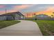 Beautiful one-story home with an extended driveway and neutral-colored exterior at sunset at 785 Orchid Grove Blvd, Davenport, FL 33837