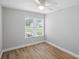 Bright bedroom featuring wood flooring, a large window with blinds, and a modern ceiling fan at 841 Wesson Ct, Casselberry, FL 32707
