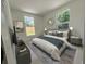 Bright bedroom featuring two windows, a decorative mirror, and a bed with a gray, white, and teal color scheme at 910 Flamingo Dr, Leesburg, FL 34748