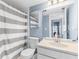 Cozy bathroom with striped shower curtain, blue walls, and a bright vanity area with a white cabinet at 1051 S Highland St # 7D, Mount Dora, FL 32757