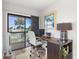 Bright home office features a wooden desk, white chair, and a sliding door to a balcony with lush green views at 1051 S Highland St # 7D, Mount Dora, FL 32757
