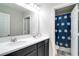 Well-lit bathroom with double sink vanity and shower/tub combo with a blue curtain at 14460 Orchard Hills Blvd, Winter Garden, FL 34787
