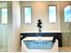 Bright bathroom featuring a modern soaking tub with a clear glass side and a decorative plant between two windows at 1733 Harmon Ave, Winter Park, FL 32789
