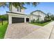 Modern home showing a detached garage, a brick driveway, and minimalist landscaping along the fence at 1733 Harmon Ave, Winter Park, FL 32789