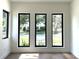 Living room with a view of mature trees through three black frame windows overlooking the street at 1733 Harmon Ave, Winter Park, FL 32789