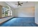 Spacious living room featuring blue carpeting, a ceiling fan, and arched window with natural light at 1879 Odham Dr, Deltona, FL 32738