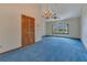 Living room with blue carpet, large windows, and a decorative chandelier at 1879 Odham Dr, Deltona, FL 32738