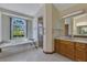 Well-lit bathroom with soaking tub, shower, and dual sinks with wood cabinets at 1879 Odham Dr, Deltona, FL 32738