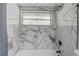 Bathtub/shower with a modern gray/white marble-look tile surround and modern fixtures at 1921 Heathwood Dr, Winter Park, FL 32792