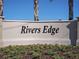 The Rivers Edge community sign is enhanced by blue skies and decorative shrubbery at 2722 Golden Trout Ln, Edgewater, FL 32141