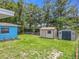 Grassy backyard with storage sheds, partially fenced in and backed by mature trees at 2728 Hertha Ave, Orlando, FL 32826