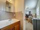 Bathroom with wooden vanity, mirror, textured walls, and a glimpse into a cluttered bedroom at 2728 Hertha Ave, Orlando, FL 32826