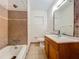Bathroom featuring neutral tiling, a tub-shower, wood vanity, toilet, and framed mirror at 2728 Hertha Ave, Orlando, FL 32826