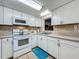The modern kitchen features white cabinets, a matching stove and microwave, and a neutral tile backsplash at 2728 Hertha Ave, Orlando, FL 32826