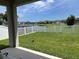 Well-manicured backyard offering a lush lawn, white fence, and a tranquil view of a pond and neighboring homes at 2824 Neverland Dr, New Smyrna Beach, FL 32168