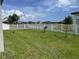 Expansive backyard with a lush green lawn, sturdy white fence, and serene water view at 2824 Neverland Dr, New Smyrna Beach, FL 32168