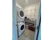 Efficient laundry room featuring a stacked washer and dryer, shelving, and convenient storage solutions at 2824 Neverland Dr, New Smyrna Beach, FL 32168