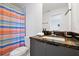 Clean bathroom featuring a gray vanity, granite countertop, and colorful shower curtain at 3308 Tranquil Trl, Kissimmee, FL 34747