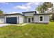 Exterior view of the home featuring a well-manicured lawn, a blue garage door, and a charming gray exterior at 4345 Sw 143Rd Lane Rd, Ocala, FL 34473