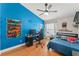 Vibrant bedroom with a gaming theme, featuring a blue accent wall and wood flooring at 462 Lakepark Trl, Oviedo, FL 32765