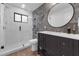 Modern bathroom with a glass walk-in shower, marble accent wall, and dark vanity with a round mirror at 4702 Shorecrest Dr, Orlando, FL 32817