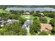 Aerial view of a white two-story home, gray tile roof, lush trees, and a golf course and lake in the background at 5074 Isleworth Country Club Dr, Windermere, FL 34786
