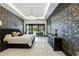 A modern bedroom features patterned wallpaper and chandelier with direct access to the backyard at 5074 Isleworth Country Club Dr, Windermere, FL 34786