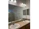 Bathroom featuring double sinks with granite countertops and a glass door shower at 512 Novara Way, Davenport, FL 33837