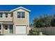 Beige two-story home featuring an attached garage, complemented by a manicured lawn and a clear blue sky at 535 Zinfandel Dr, Daytona Beach, FL 32117