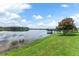 Scenic lake view with a wooden pier extending into the water, surrounded by lush green grass and a serene atmosphere at 5819 Covington Cove Way, Orlando, FL 32829