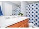 Updated bathroom featuring a double sink vanity, wooden cabinets and a shower tub with a floral curtain at 609 Big Pine Ave, Minneola, FL 34715
