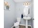 Cozy powder room boasts pedestal sink, oval mirror, and soft blue walls at 609 Big Pine Ave, Minneola, FL 34715