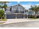 Townhome featuring a gray exterior, multiple garage doors, and quaint second-story balconies with lush green trees at 6484 S Goldenrod Rd # 41A, Orlando, FL 32822