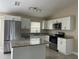 Well-lit kitchen with stainless steel appliances, granite countertops, white cabinets and island at 739 Parrot Ct, Poinciana, FL 34759