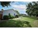 Landscaped backyard with green grass, trees, and view of home's side exterior at 759 Lake Como Dr, Lake Mary, FL 32746