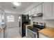 Practical kitchen featuring white cabinets, granite countertops, stainless steel appliances, and tiled floors at 879 Tamerlane St, Deltona, FL 32725