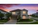Charming two-story home featuring stone accents, a paved driveway, and lush landscaping at dusk at 8951 Hilton Ridge Ave, Kissimmee, FL 34747