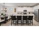 Open-concept kitchen with white cabinets, stainless appliances, island seating and adjacent dining area at 8951 Hilton Ridge Ave, Kissimmee, FL 34747