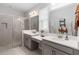 Bright bathroom features dual sinks, white countertops, modern fixtures, large mirror, and a glass-enclosed shower at 971 Braewood Dr, Clermont, FL 34715