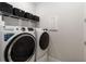 Well-equipped laundry room features a front-load washer, dryer, shelving, and ample space for laundry tasks at 971 Braewood Dr, Clermont, FL 34715