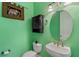 Compact half bathroom with green walls, unique vanity, and decorative mirror at 1615 Wilson Ave, Orlando, FL 32804