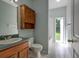 Bathroom with wooden vanity, tiled floor, toilet and shower/tub combo with open door to the backyard at 2237 Wintermere Pointe Dr, Winter Garden, FL 34787
