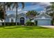 Charming blue home boasts a well-manicured lawn, lush landscaping, and swaying palm trees at 2237 Wintermere Pointe Dr, Winter Garden, FL 34787