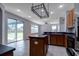 Open kitchen with island, black countertops, wooden cabinets, and sliding glass doors to the backyard at 2237 Wintermere Pointe Dr, Winter Garden, FL 34787