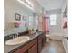 Bathroom featuring a tiled shower, sink, toilet, mirror, and floral decorations at 2579 Woodside Ridge Dr, Apopka, FL 32712