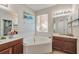 Bright bathroom featuring a tiled tub, natural light, and and sinks with wooden cabinets at 2579 Woodside Ridge Dr, Apopka, FL 32712