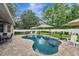 Beautiful backyard features a kidney-shaped pool with a spa, surrounded by lush landscaping and a spacious patio area at 2579 Woodside Ridge Dr, Apopka, FL 32712