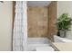 This bathtub with shower includes neutral tile, a white shower curtain, and decorative plant at 308 N Shadowbay Blvd # 214, Longwood, FL 32779
